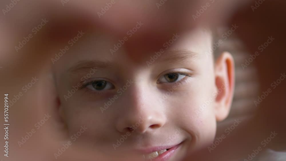 portrait of a cute caucasian boy 8-9 years old looking through his hands in the shape of a heart, the child shows a gesture in the shape of a heart. selective focus. loving boy looking at camera portrait of a cute caucasian boy 8-9 years old looking through his hands in the shape of a heart, the child shows a gesture in the shape of a heart. selective focus. loving boy looking at camera