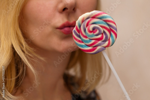 woman lips with candie. Young blonde lady holding big colorful lollipop