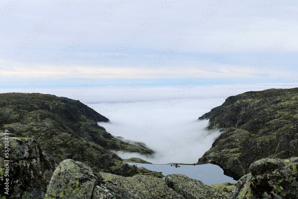 View from the top of the mountain of the Serra da Estrela natural park in Portugal. Cloudy and foggy day. Small water dam in the middle of the mountains. View from the top of the mountain of the Serra da Estrela natural park in Portugal. Cloudy and foggy day. Small water dam in the middle of the mountains.