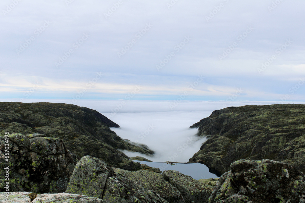View from the top of the mountain of the Serra da Estrela natural park in Portugal. Cloudy and foggy day. Small water dam in the middle of the mountains.