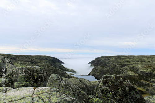 View from the top of the mountain of the Serra da Estrela natural park in Portugal. Cloudy and foggy day. Small water dam in the middle of the mountains.