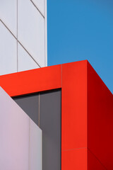 Exterior architecture background. Geometric pattern of red, gray and white aluminum composite tile wall outside of modern office building in minimal style and vertical frame