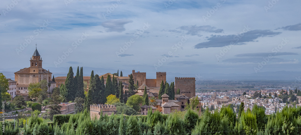 Fototapeta premium Amazing panorama of Granada city and Alhambra's Alcazaba fortress. Scenic view from Generalife gardens on a sunny day with blue sky above. Granada, Andalusia, Spain. 