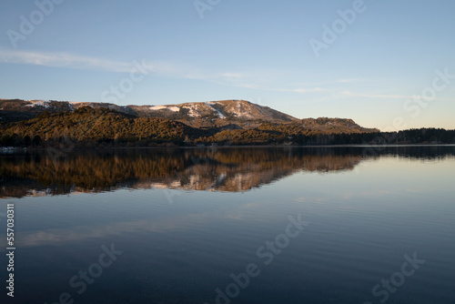 Serene landscape. View of the calm lake  mountains and forest at sunset. The blue sky and environment reflection in the water surface. 
