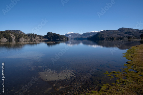 Summer day in the lake. The reflection of the blue sky  green forest and mountains in the lake s water surface.