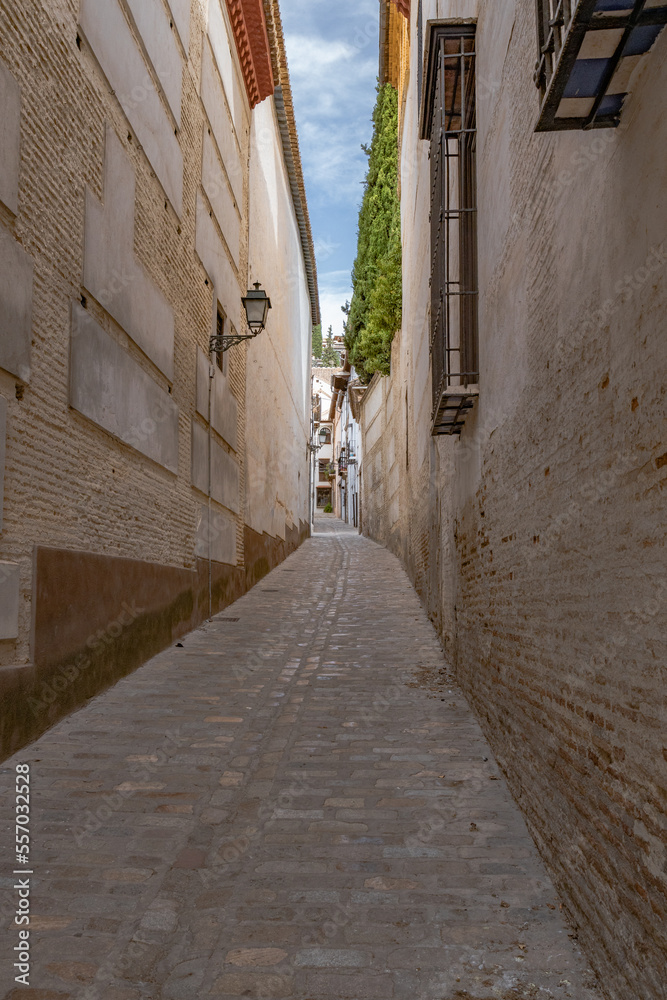 Granada, Spain, 21st of October, 2022. On the way to the Alhambra  Palace. Carrera Del Darro street with small souvenir shops and walking tourists. Narrow cobbled street of Granada in sunshine.       