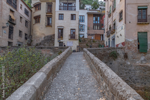 Fototapeta Naklejka Na Ścianę i Meble -  Granada, Spain, 21st of October, 2022. On the way to the Alhambra  Palace. Carrera Del Darro street with small souvenir shops and walking tourists. Narrow cobbled street of Granada in sunshine.       