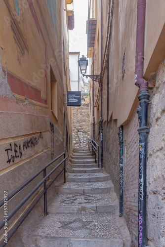 Fototapeta Naklejka Na Ścianę i Meble -  Granada, Spain, 21st of October, 2022. On the way to the Alhambra  Palace. Carrera Del Darro street with small souvenir shops and walking tourists. Narrow cobbled street of Granada in sunshine.       