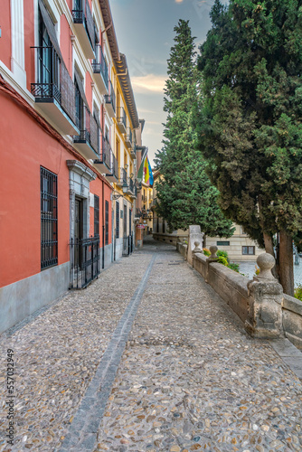 Fototapeta Naklejka Na Ścianę i Meble -  Granada, Spain, 21st of October, 2022. On the way to the Alhambra  Palace. Carrera Del Darro street with small souvenir shops and walking tourists. Narrow cobbled street of Granada in sunshine.       