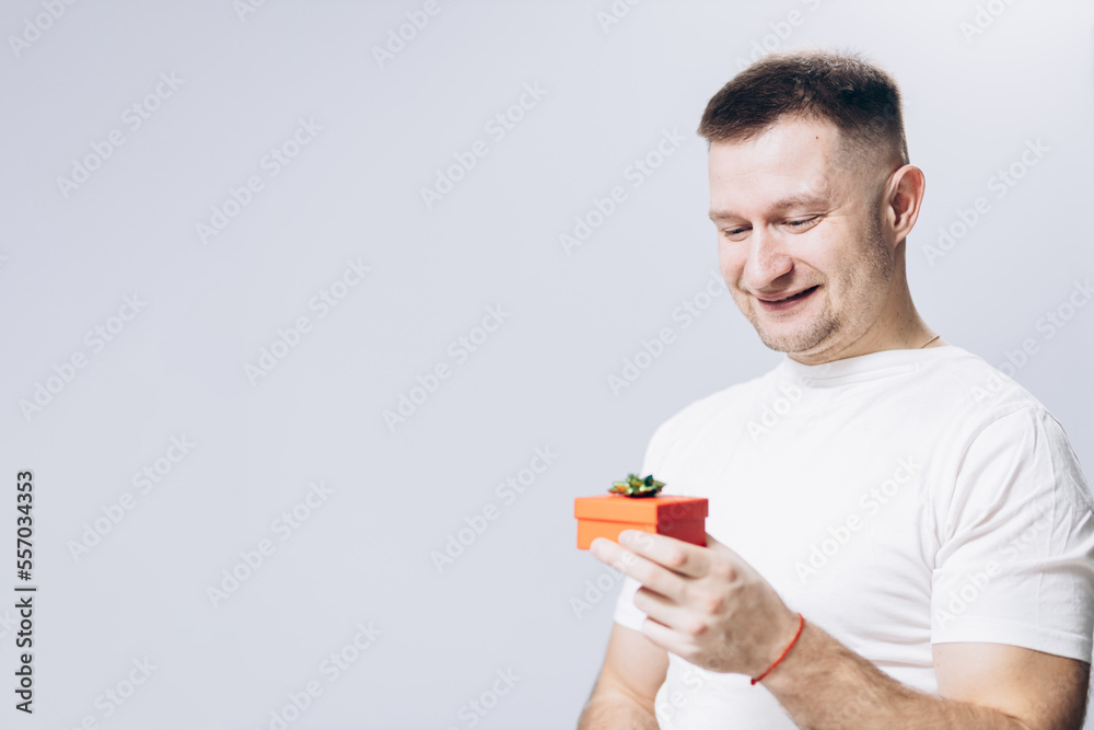 A man in a white t-shirt holds a birthday and valentine's day gift in his hand A man in a white t-shirt holds a birthday and valentine's day gift in his hand