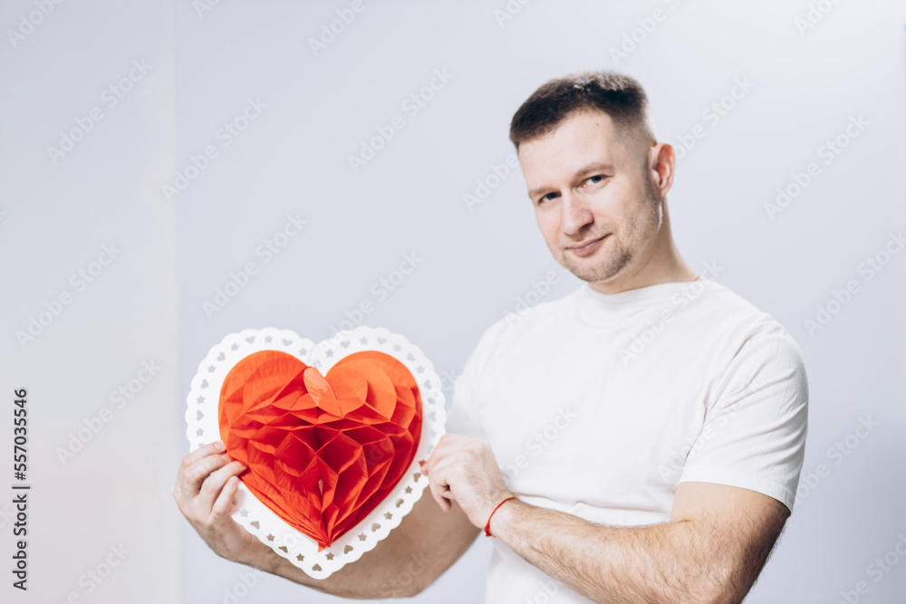 A man in a white t-shirt is holding a big red heart. Valentine's Day A man in a white t-shirt is holding a big red heart. Valentine's Day