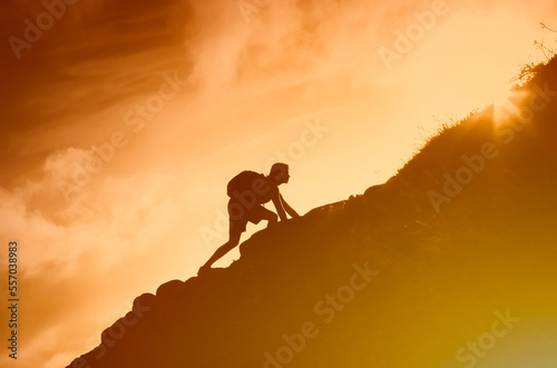 Brave man climbing up steep rocky mountain cliff.