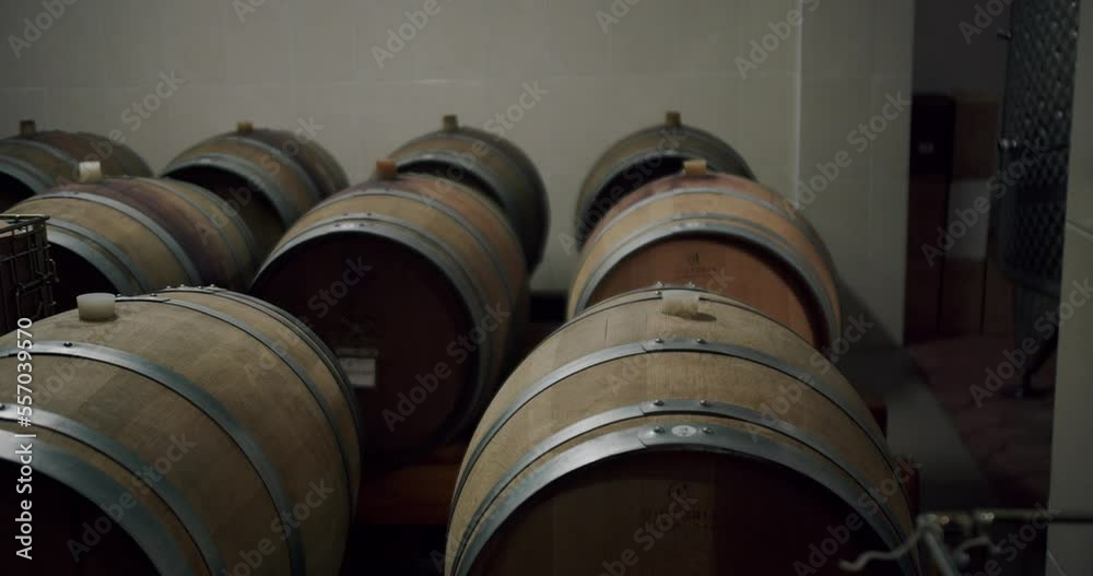 Brown wooden barrel. Traditional winery. Aged wooden barrels with a wine, brandy or whiskey in a big warehouse. Oak Barrels stacked In a dark Wine Cellar or basement. Brown wooden barrel. Traditional winery. Aged wooden barrels with a wine, brandy or whiskey in a big warehouse. Oak Barrels stacked In a dark Wine Cellar or basement.