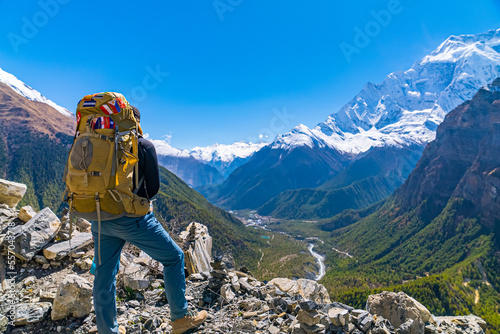 Female Trekker with large backpack looking at view on the Annapurna Circuit Trek on a sunny cloudless fall day photo