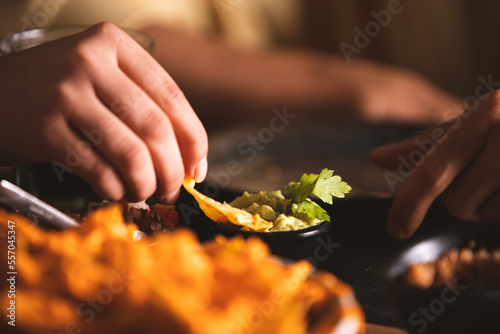 woman dipping a nacho in cheese
