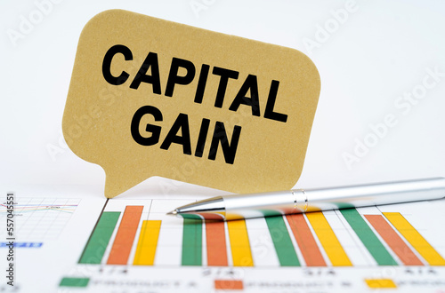 On the financial charts lies a pen and a sign with the inscription - capital gain