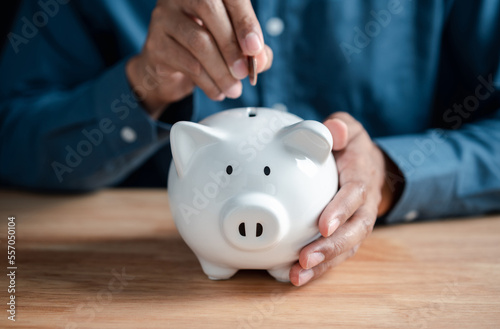 Man putting coin to white piggy bank for deposit banking of investment , retirement planning future saving, invest for profit and interest concept.