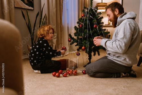 Father and son decorating Christmas tree in living room
