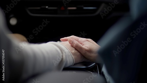 CU view of beautiful 60s mature senior grey haired Caucasian couple riding in a car, holding hands while traveling together