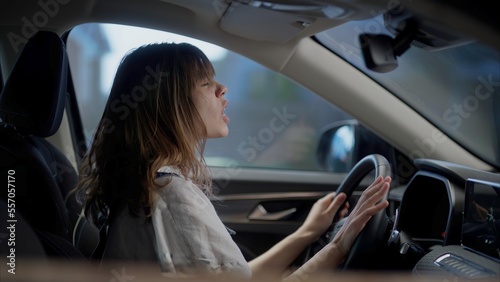 Caucasian female dancing and singing to her favorite song while driving the car during the suburbs neighborhood © supamotion