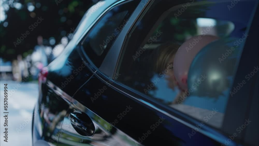 Happy positive birthday girl riding on a back seat of a car surrounded with balloons Happy positive birthday girl riding on a back seat of a car surrounded with balloons