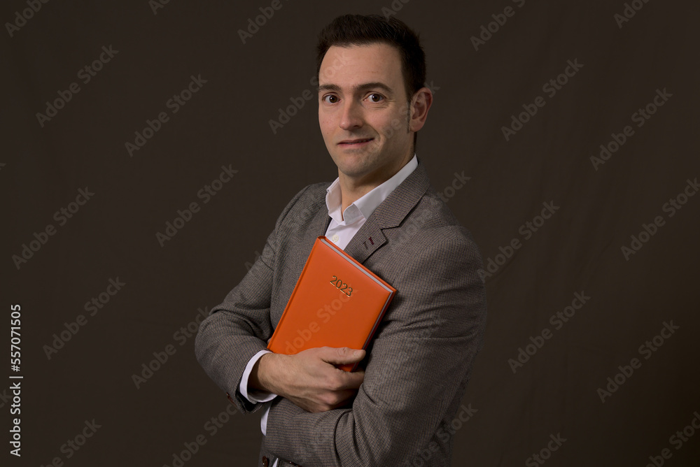 Professional Elegant formal self employed smiles and holds a 2023 orange agenda. Concept new year resolution in business. High quality photo Professional Elegant formal self employed smiles and holds a 2023 orange agenda. Concept new year resolution in business. High quality photo