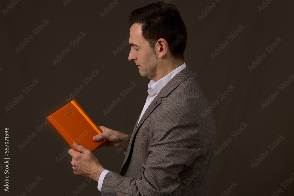 Smart executive office worker of a company holding a 2023 orange agenda expecting success. Concept new year resolution in business. High quality photo Smart executive office worker of a company holding a 2023 orange agenda expecting success. Concept new year resolution in business. High quality photo