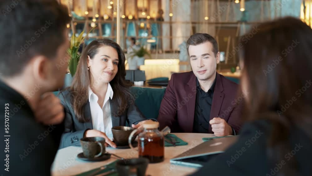 Group of suit wearing colleagues discussing working situation sitting at table in cafe with laptop. Casual coworkers having sparkling conversation in reastaurant. Concept of teambuilding, leisure. Group of suit wearing colleagues discussing working situation sitting at table in cafe with laptop. Casual coworkers having sparkling conversation in reastaurant. Concept of teambuilding, leisure.