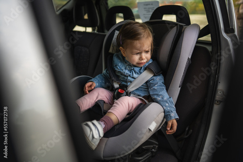 one small caucasian girl female toddler sit in the car safety seat cry