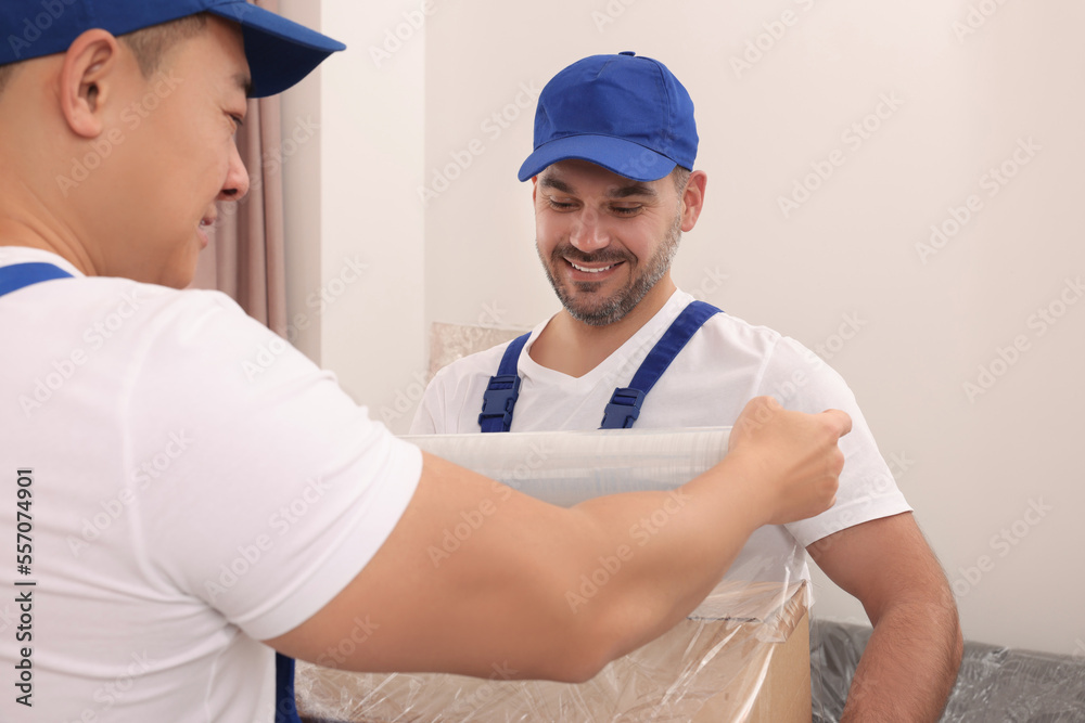 Workers wrapping box in stretch film indoors Workers wrapping box in stretch film indoors