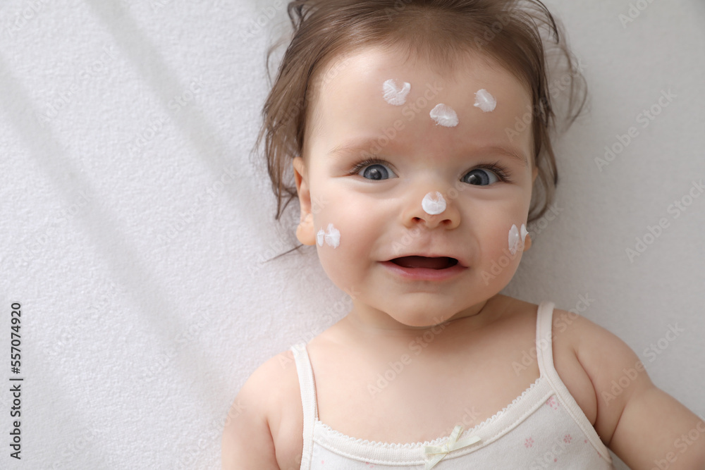 Naklejka premium Cute little baby with cream on face in comfortable crib, top view. Space for text