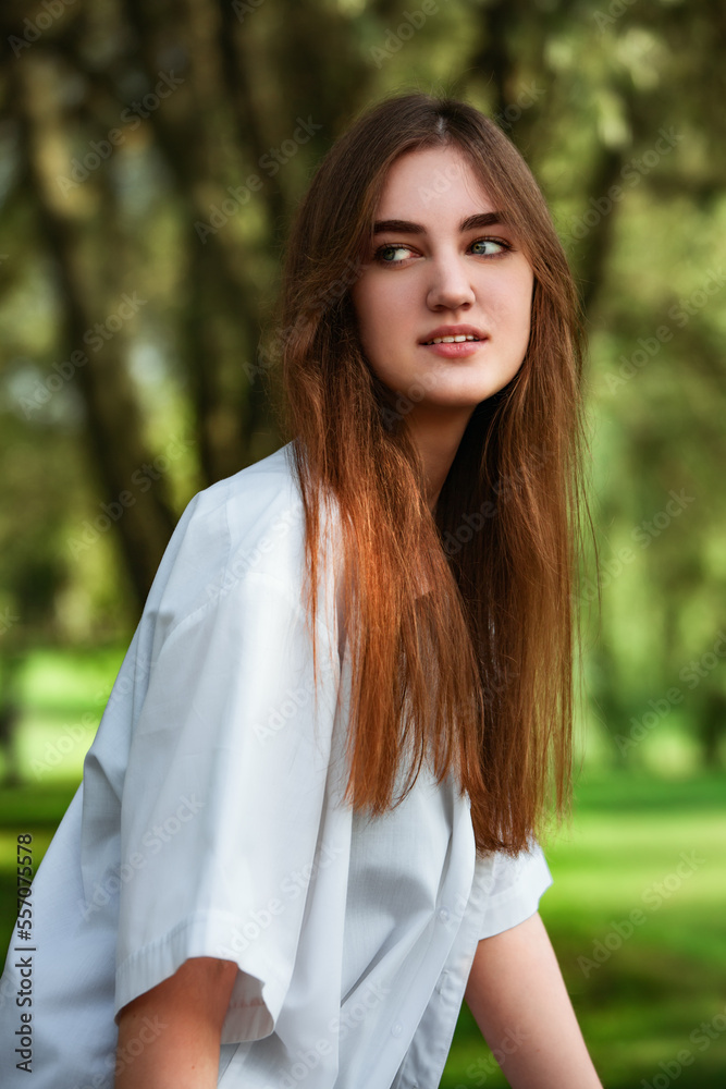 Beautiful toothy smiling teen woman looking happy outdoors in white shirt on summer green trees background. Closeup portrait Beautiful toothy smiling teen woman looking happy outdoors in white shirt on summer green trees background. Closeup portrait