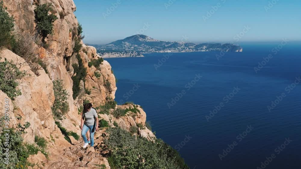 Women tourists climbing on rocky mountain Penon de Ifach, Calpe, Spain Women tourists climbing on rocky mountain Penon de Ifach, Calpe, Spain