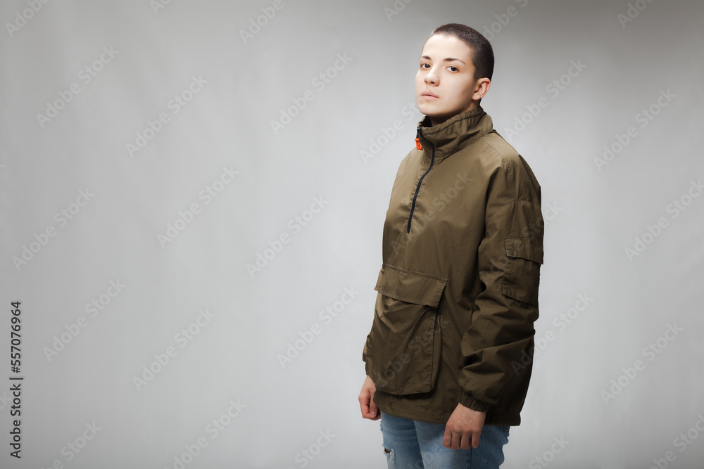 Girl with short hair wearing jacket and jeans against gray background. . Girl with short hair wearing jacket and jeans against gray background. .
