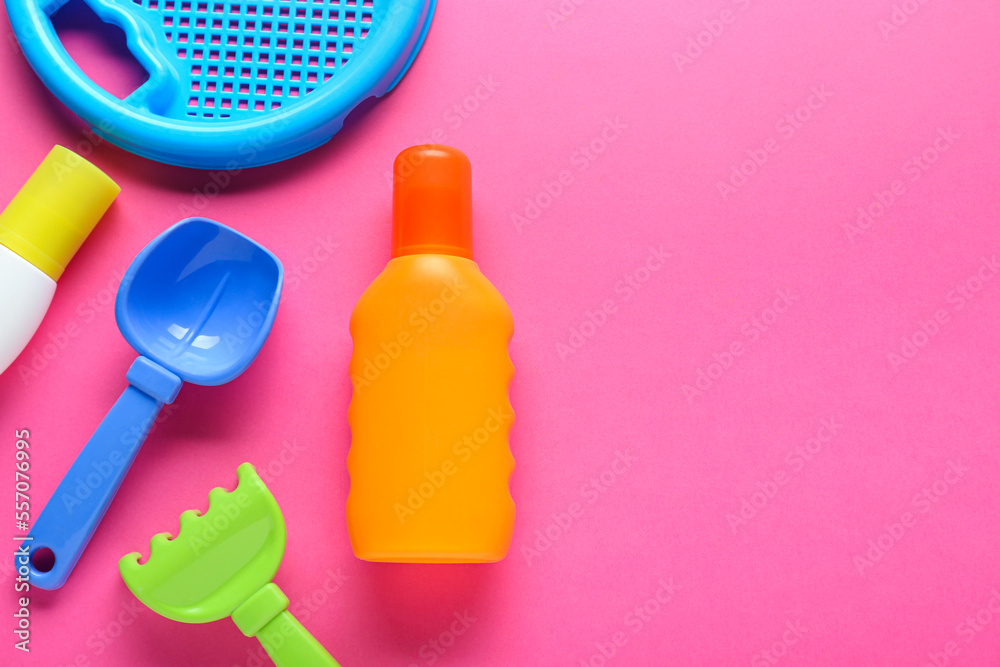 Bottle of suntan cream and children's beach toys on pink background, flat lay. Space for text Bottle of suntan cream and children's beach toys on pink background, flat lay. Space for text