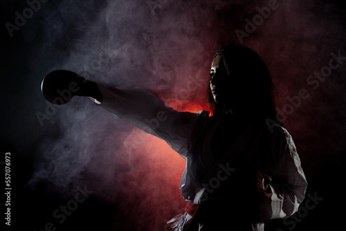 beautiful girl exercising karate punch against red fog background..