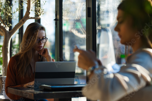 Free Download Two young business women in a cafe having one on one meeting. Friends after work talking gossiping and having coffee at a window table on a sunny day.. - GFXLoad