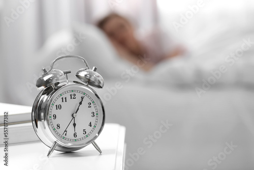 Woman sleeping at home in morning, focus on alarm clock. Space for text