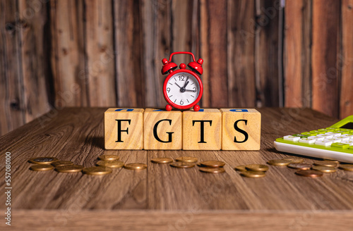 As iniciais FGTS de Fundo de Garantia do Tempo de Serviço com um relógio despertador, moedas e uma calculadora na composição. photo
