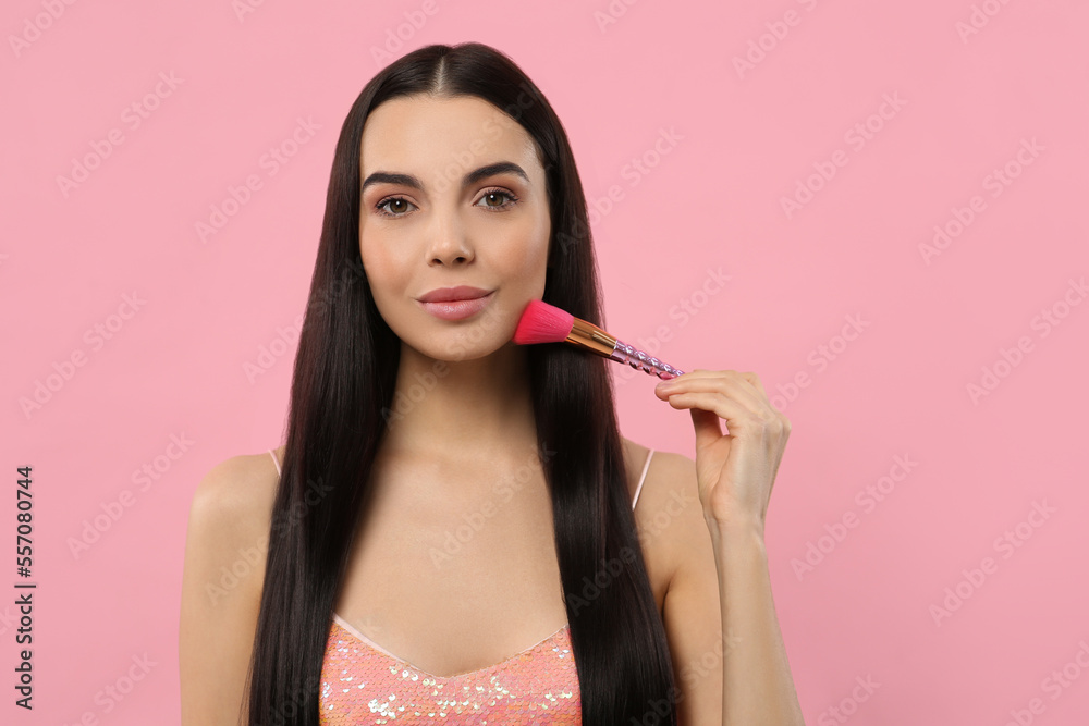 Beautiful woman applying makeup with brush on pink background. Space for text Beautiful woman applying makeup with brush on pink background. Space for text
