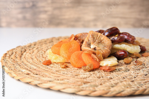 Pile of different tasty dried fruits on wicker mat  closeup. Space for text