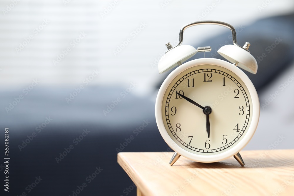 White alarm clock on wooden nightstand in bedroom, space for text White alarm clock on wooden nightstand in bedroom, space for text