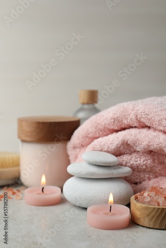 Beautiful composition with burning candles and different spa products on light grey table