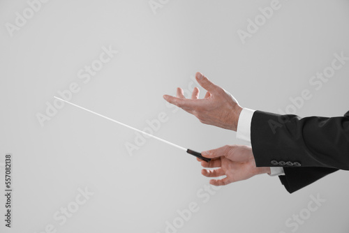 Bilde på lerret Professional conductor with baton on light grey background, closeup