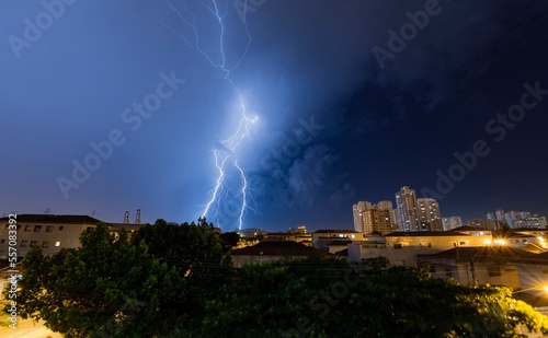 Lightning in the blue sky of the city. Summer storm. Thunder, lightning and rain at night. Santos, Brazil.  photo