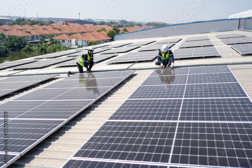 Engineer on rooftop kneeling next to solar panels photo voltaic with tool in hand for installation