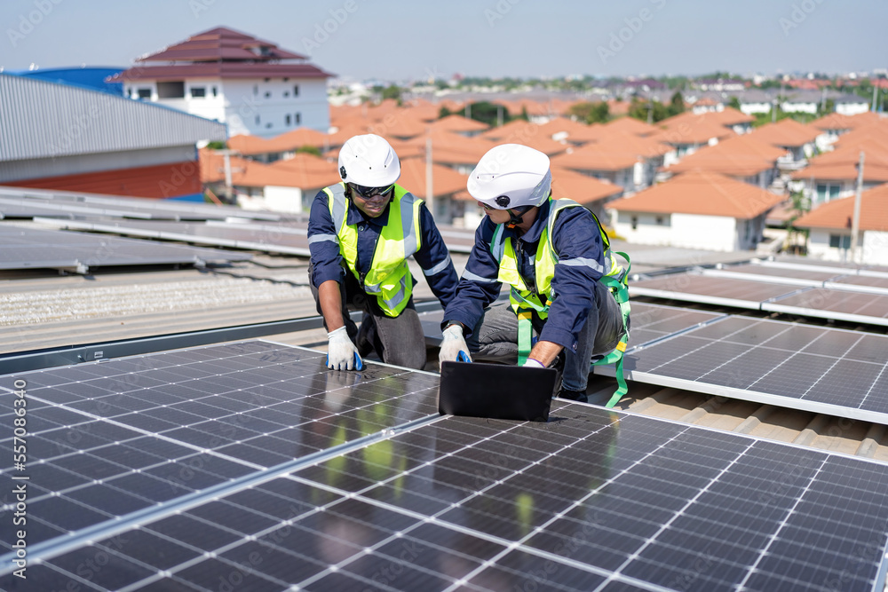 Engineer on rooftop kneeling next to solar panels photo voltaic check laptop for good installation Engineer on rooftop kneeling next to solar panels photo voltaic check laptop for good installation