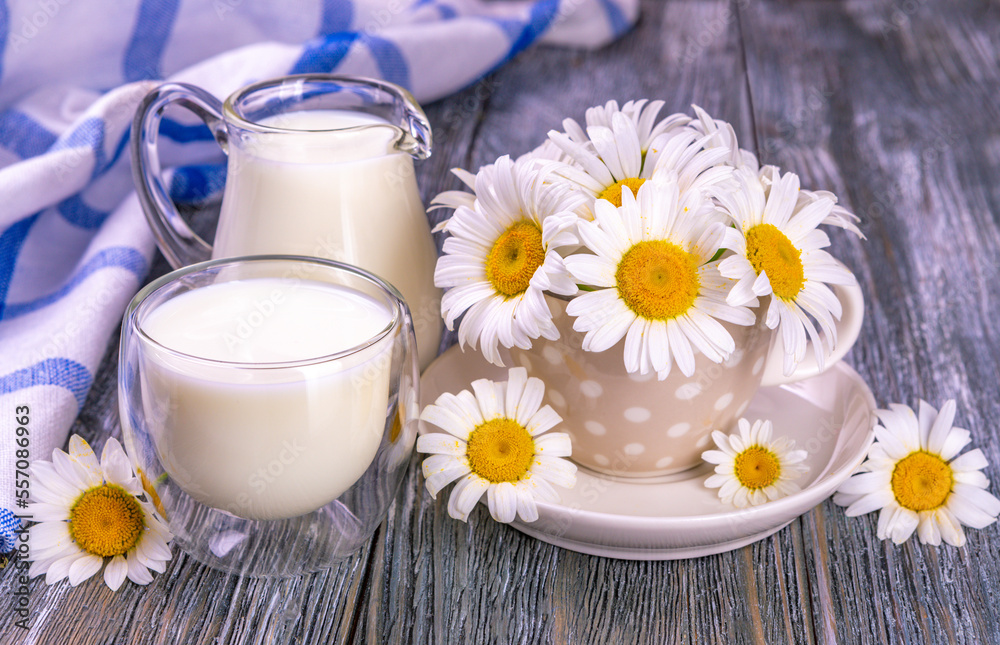Milk in a glass and chamomile in a tea cup on a wooden table. Milk in a glass and chamomile in a tea cup on a wooden table.
