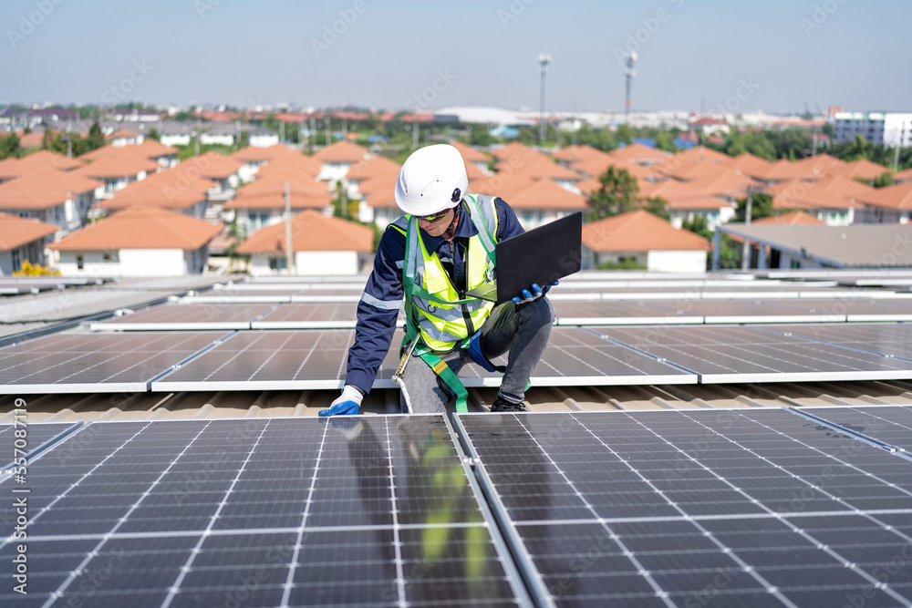 Engineer on rooftop kneeling next to solar panels photo voltaic with tool in hand for installation Engineer on rooftop kneeling next to solar panels photo voltaic with tool in hand for installation