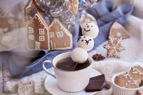 Winter aesthetic morning. Marshmallow snowman in hot chocolate, ginger cookies near Christmas tree. Cozy warm home.